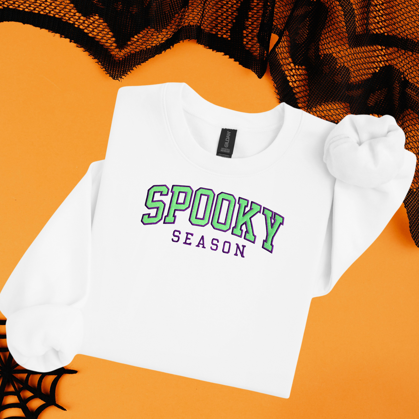 White sweatshirt with 'Spooky Season' text on an orange background