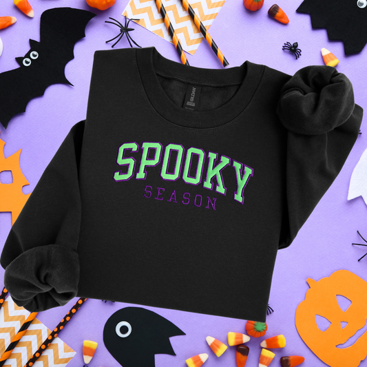Black sweatshirt with 'Spooky Season' text on a Halloween-themed background
